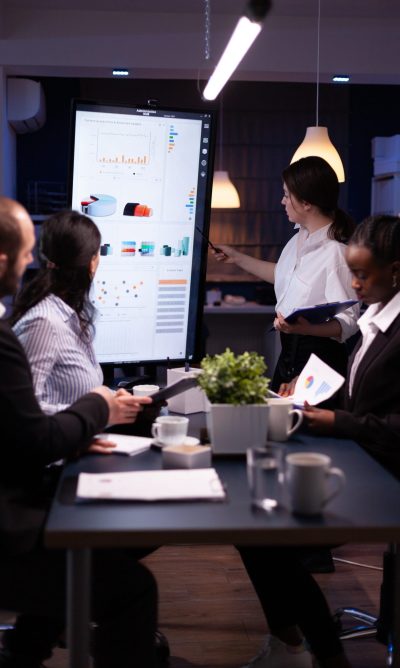 delaPlex Article Data Analytics Outsourcing INSIDE IMAGE 1 Diverse multiethnic business teamwork overworking in office meeting room analyzing financial graphs late at night. Coworkers brainstorming project ideas solving company problem.